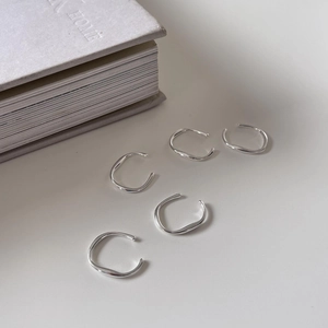 Detailed view of five minimalist silver rings with polished finishes on a white surface