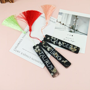 Détail de trois marque-pages en résine faits main avec fleurs séchées et pompons