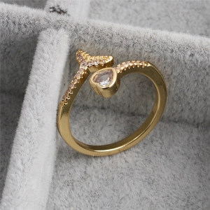 Golden open heart ring with sparkling zircon stones on a soft grey jewelry box background