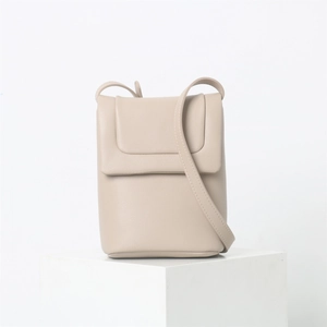 Détail macro du sac de téléphone en cuir souple beige avec rabat et bandoulière fine
