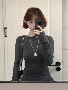 Long collier pendentif étoile argenté assorti à un pull en maille gris foncé ajusté