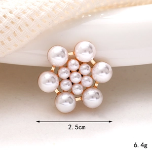 Macro detail of 2.5cm pearl floral charm with gold base on white fabric background