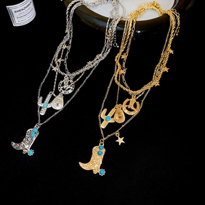 Macro detail of western-style layered necklace with turquoise boot and cactus charms