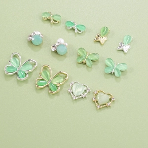 Detailed view of mint green cat-eye butterfly and heart nail art charms with pearls