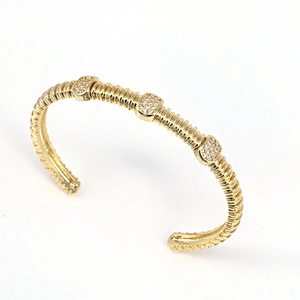 Detail of gold-plated open cuff bracelet with spiral texture and white zircon inlay