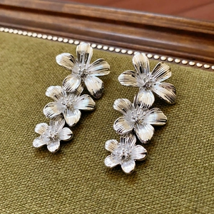 Macro shot of silver tiered floral earrings featuring brushed metal texture and fine details