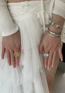 Close-up of gold and silver sunburst rings paired with textured silver bangles