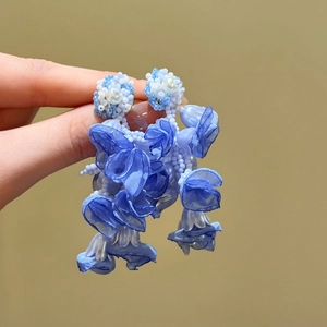 Close-up of blue crystal flower tassel earrings with intricate beadwork and fabric petals