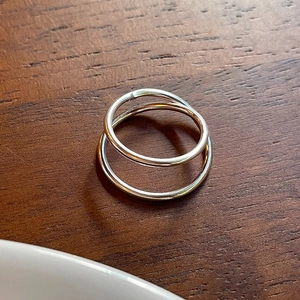 Detailed view of intertwined double-loop silver ring on dark wood surface texture
