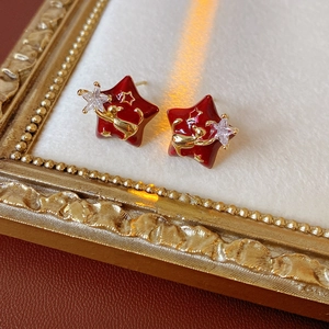 Detail of red star earrings with gold reindeer and zircon inlay on a vintage frame