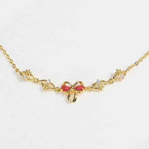 Gold-tone heart bow bracelet with red stones and white zircon flower details