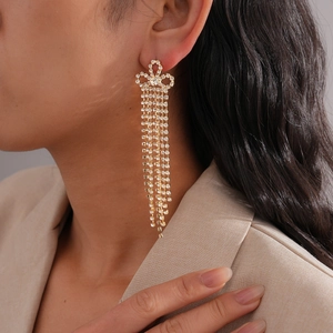 Gros plan de boucles d'oreilles dorées à pampilles avec nœud en strass sur un mannequin