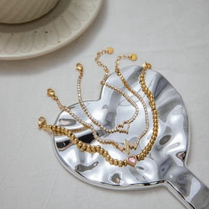 Close-up of gold beaded and zircon tennis bracelets with heart and lightning charms