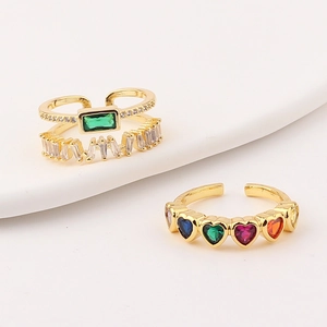 Detail of adjustable gold rings with green emerald zircon and colorful heart-shaped stones