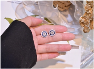 Macro detail of round evil eye stud earrings with blue and white zircon stones