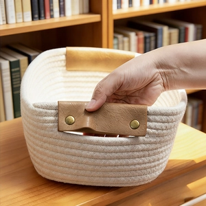 Close-up of a woven cotton rope storage basket with leather handles and metal rivets