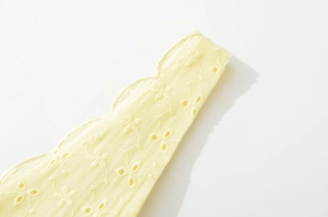 Détail d'une robe d'été jaune clair montrant la broderie florale et la texture ajourée