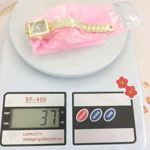 Close-up of luxury gold crystal watch on digital scale showing weight of 37g