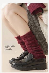 Gros plan de jambières en tricot bordeaux avec mocassins noirs et boucle métallique