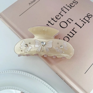 Macro view of beige acetic hair claw with rhinestone heart and white bow pattern