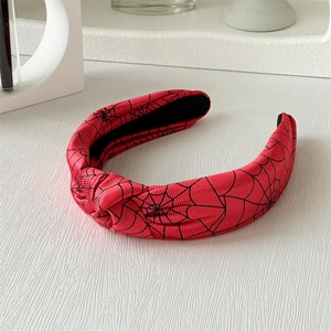 Détail d'un serre-tête d'Halloween rouge avec des motifs de toile d'araignée noire noués