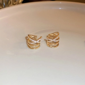 Macro shot of gold crisscross multi-layer ear cuff with shimmering zircon stone inlay
