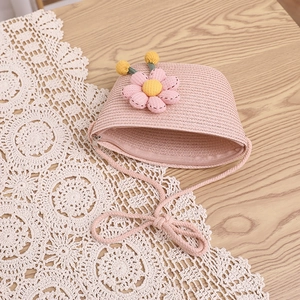 Gros plan d'un sac bandoulière en paille rose avec fleur en peluche sur dentelle