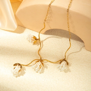 Vintage gold snake chain necklace featuring white bead pendants and tassel detailing