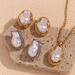 Close-up of baroque pearl necklace and earrings set on stone in gold and silver