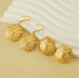 Close-up of gold flower earrings showing detailed petal textures and metallic finish