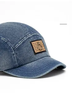 Detail of vintage washed blue denim baseball cap with brown square patch and metal ring