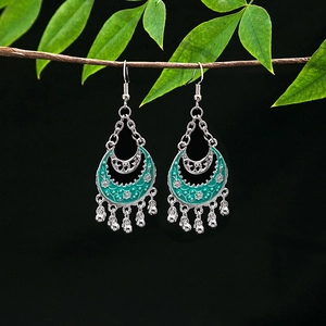 Detail of vintage silver boho earrings with blue enamel crescent and bead tassels