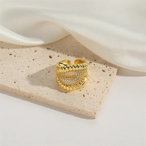 Detailed view of adjustable golden wide-band ring with braided texture and tiny zircons