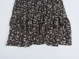 Close-up of elegant floral dress hem with layered ruffle detail and lightweight fabric