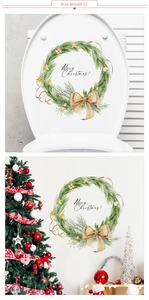 Close-up of a festive Christmas pine wreath sticker featuring a plaid bow on a white wall