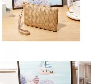 Detail of a beige woven straw wristlet wallet with a faux leather strap and golden zipper
