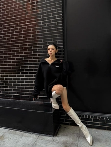Dettaglio felpa con cappuccio oversize nera con mezza zip e logo bianco sul davanti
