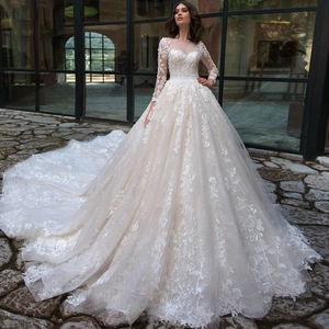 Close-up of elegant long-sleeve lace wedding dress with ball gown skirt and long train
