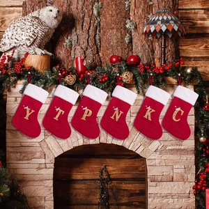 Red knitted Christmas stockings with gold initials on a festive fireplace mantel decor
