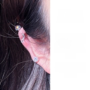 Close-up of titanium steel ear studs featuring faceted crystal balls and droplet charms