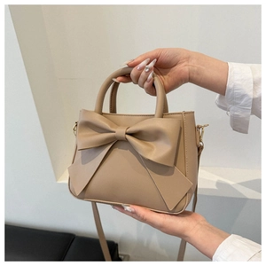 Close-up of beige bow handbag with PU leather texture and stylish top handle design