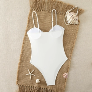 Flat lay detail of a white minimalist one-piece swimsuit with sea shells and pearls