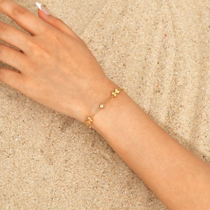 Bracelet papillon doré pour filles avec zircone cubique sur un fond de plage d'été