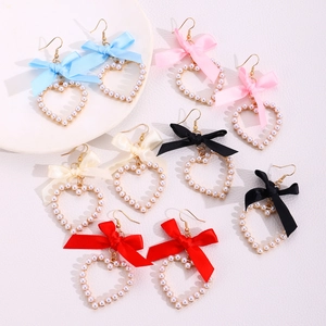 Vue à plat de boucles d'oreilles cœur en perles avec nœuds en ruban coloré