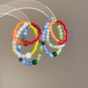Close-up of colorful natural stone beaded rings on minimalist acrylic display stands