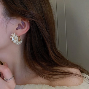 Boucles d'oreilles créoles fleurs en acrylique blanc avec base dorée sur un mannequin