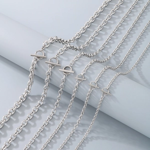 Minimalist silver stainless steel toggle clasp necklaces arranged on a grey pillar display