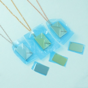 Three minimalist stainless steel envelope pendant necklaces in gold, rose gold and silver