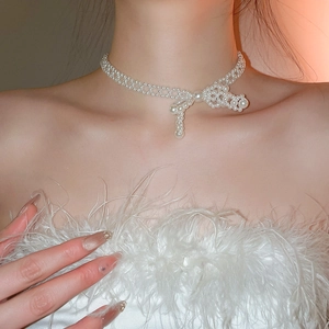 Détail du collier de perles à double couche avec pendentif nœud sur le cou d'un modèle