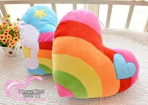 Detail of soft heart-shaped plush pillows featuring rainbow stripes and star patterns